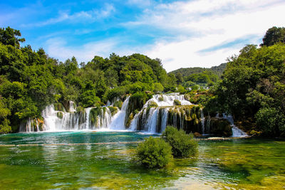 Scenic view of waterfall in forest against sky