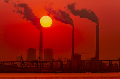 Smoke emitting from factory against sky during sunset