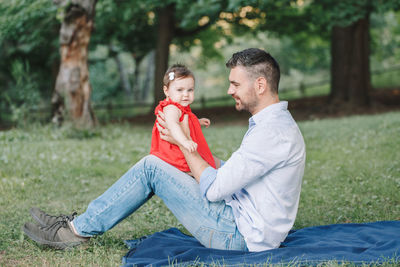 Side view of couple sitting on field