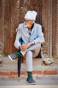 Full length portrait of man sitting outdoors