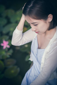 High angle view of thoughtful woman looking away while sitting by lake