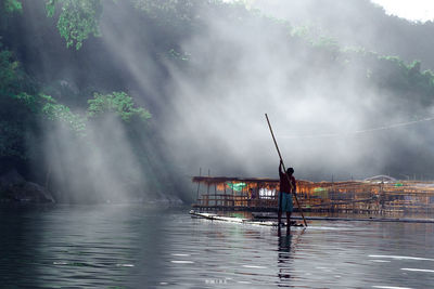 Man rowing boat in lake during sunny day