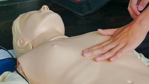 Cropped hand of paramedic practicing cpr on mannequin
