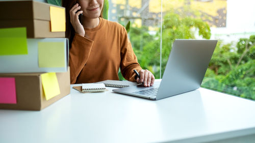 Midsection of businesswoman using laptop on table