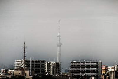 Communications tower in city against clear sky