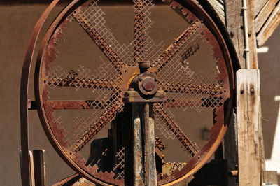 Close-up of rusty wheel against old building