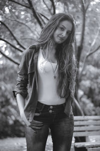 Portrait of young woman standing against tree