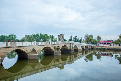 Arch bridge over river against sky