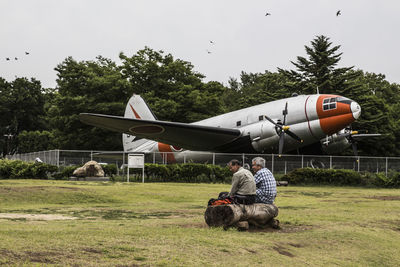 Man sitting on field against sky
