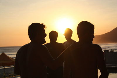 Rear view of silhouette men against sunset sky