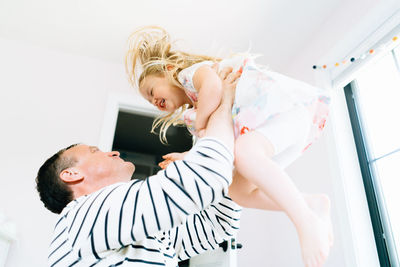 Closeup view of a father lifting his daughter into the air