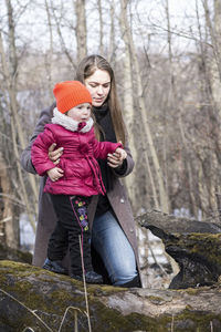 Woman holding umbrella standing by tree