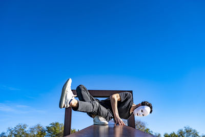 Man holding umbrella against clear blue sky