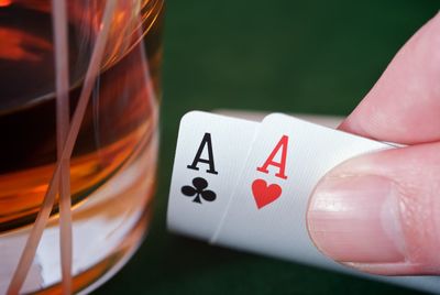 Cropped image of hand holding cards by drink on table