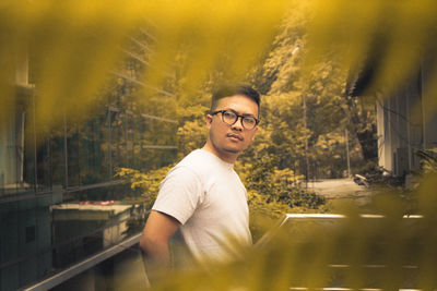 Thoughtful man wearing eyeglasses seen through leaves