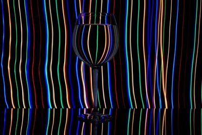 Close-up on wine glass against striped lights