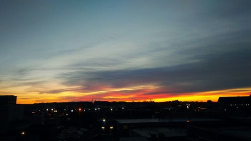 Illuminated cityscape against sky at sunset