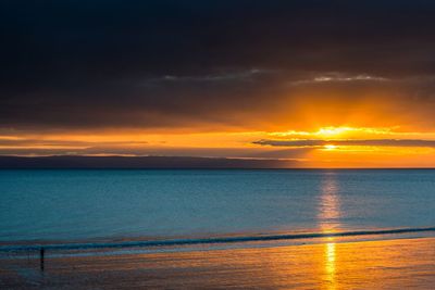 Scenic view of sea against dramatic sky during sunset