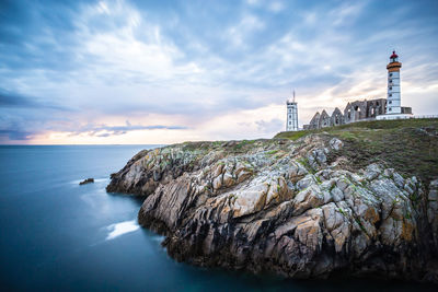 The ruins of the abbey of saint-mathieu and the lighthouse in sunset, finistere, brittany, france