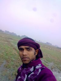 Portrait of young man standing on land against sky