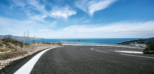 Scenic view of road by sea against sky