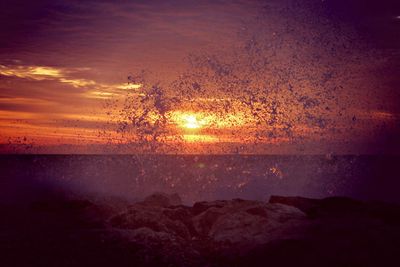 Scenic view of sea against dramatic sky during sunset