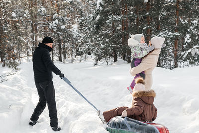 Cheerful family on a weekend rides a sleigh in a snowy forest. high quality photo