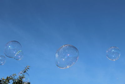 Low angle view of bubbles against blue sky