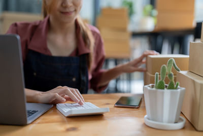 Midsection of woman using mobile phone on table