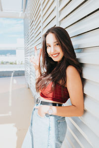 Portrait of young woman standing against wall