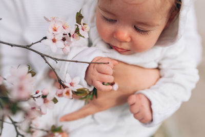 Cute baby girl looking at flowers