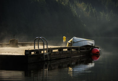 Boat moored by pier on lake against sky