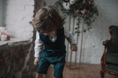 Rear view of boy standing against wall