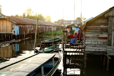 Sailboats moored in canal by houses against sky