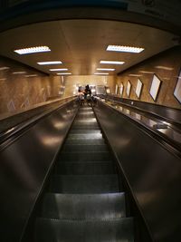 Rear view of woman walking on escalator at subway station