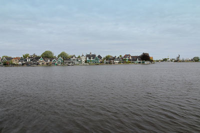 Scenic view of river by buildings against sky