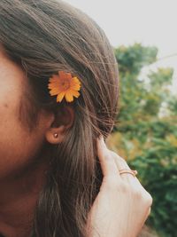 Close-up of woman wearing orange flower in hair