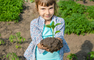 Portrait of smiling girl holding mud with plant