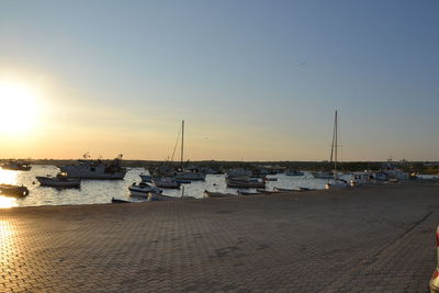 Boats moored in harbor at sunset