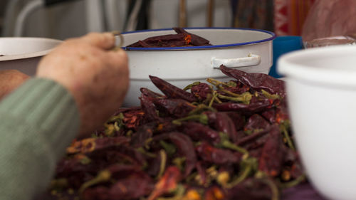 Cropped hands with red chili peppers on table