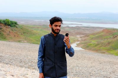 Young man standing against mountain