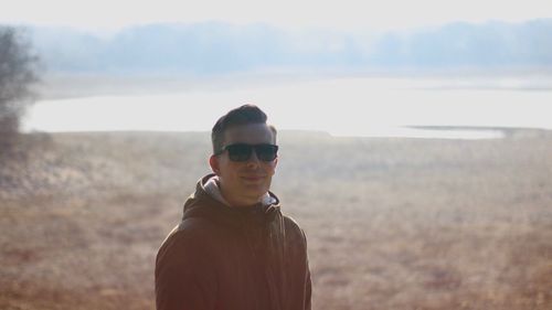 Portrait of man wearing sunglasses standing on landscape against sky