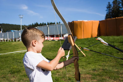 Boy playing on field against sky