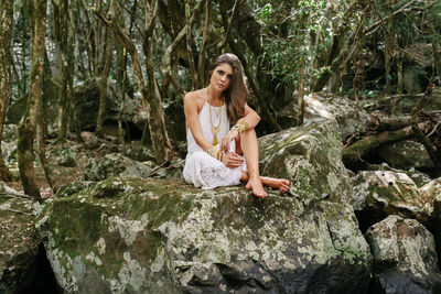 Portrait of beautiful young woman sitting on rock