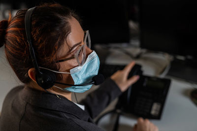 Rear view of woman using mask looking away at office