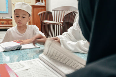 Boy reading koran while sitting at home