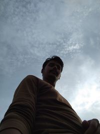 Low angle view of man looking away against sky