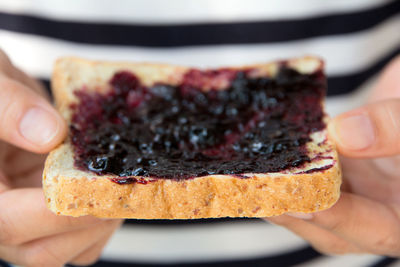 Midsection of person holding jam spread on bread