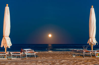 Deck chairs on beach against sky