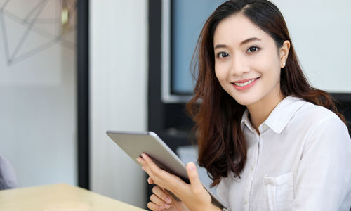 Portrait of young woman using mobile phone at home